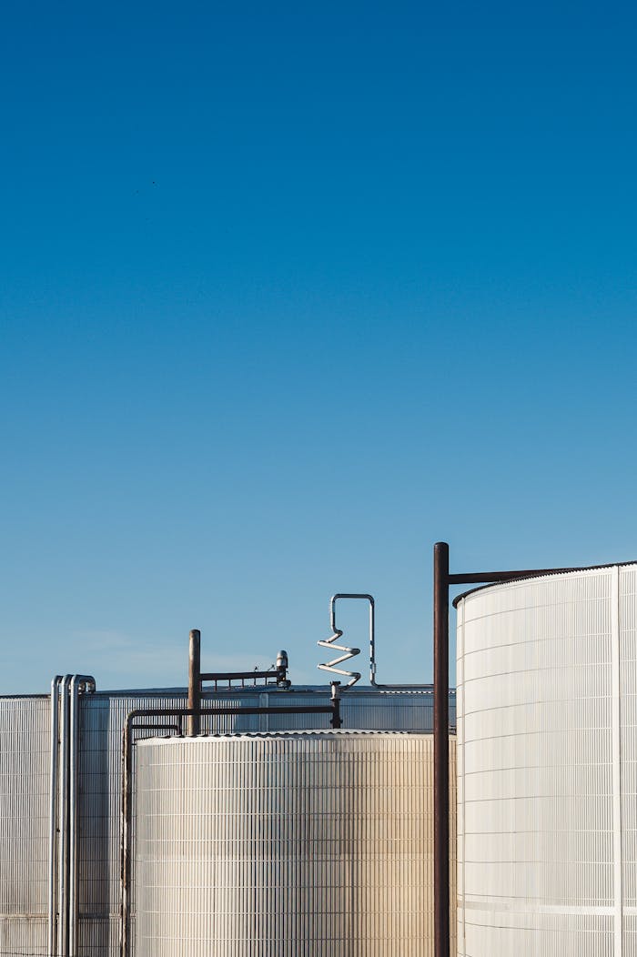 Minimalist photo of large industrial tanks under clear blue sky.